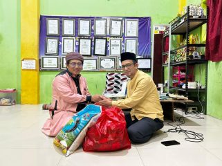 Ketua PWI Bontang Kusnadi (kanan) saat menyerahkan bantuan sembako kepada pimpinan pondok pesantren, Ustadz Khumaini Rosadi. (PWI Bontang)