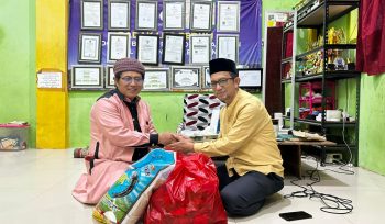 Ketua PWI Bontang Kusnadi (kanan) saat menyerahkan bantuan sembako kepada pimpinan pondok pesantren, Ustadz Khumaini Rosadi. (PWI Bontang)