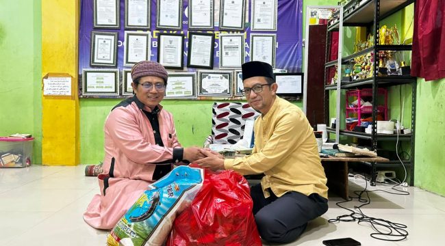 Ketua PWI Bontang Kusnadi (kanan) saat menyerahkan bantuan sembako kepada pimpinan pondok pesantren, Ustadz Khumaini Rosadi. (PWI Bontang)